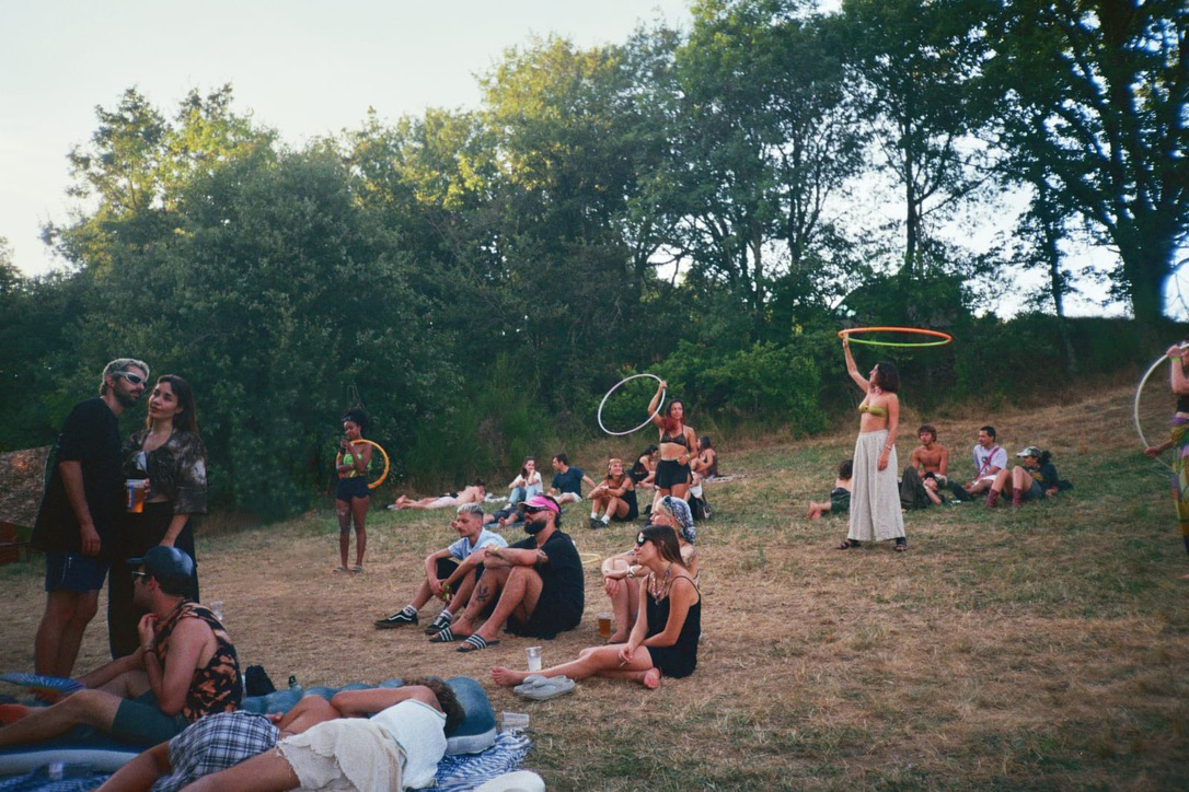 People relaxing on a grassy slope with hula hoops